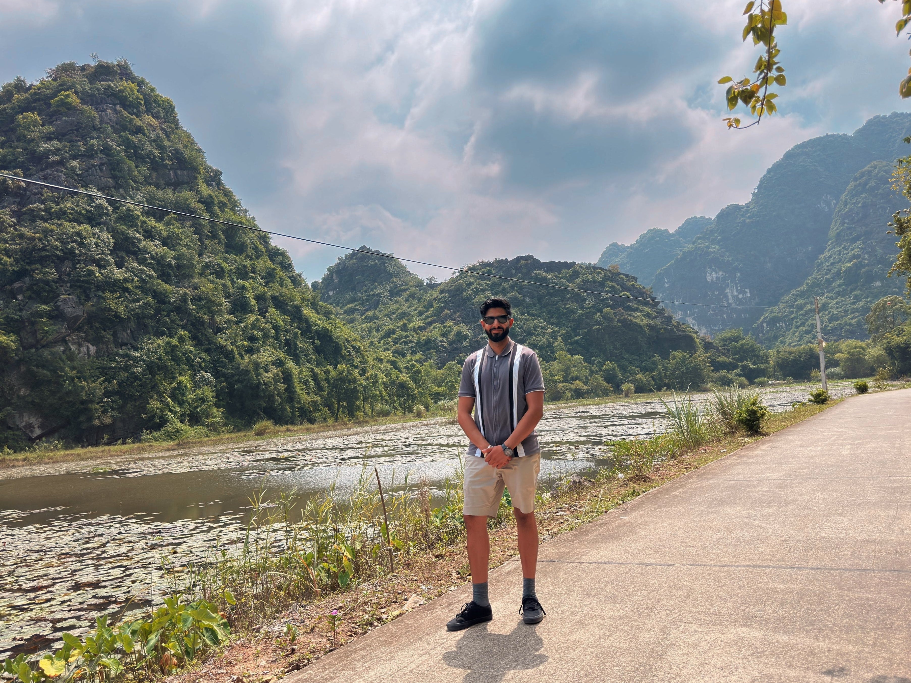 Person standing on a road with scenic mountains and a river in the background